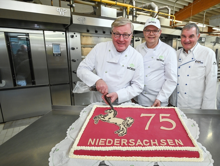 Minister Althusmann verziert eine Torte zum 75. Geburtstag Niedersachsens.