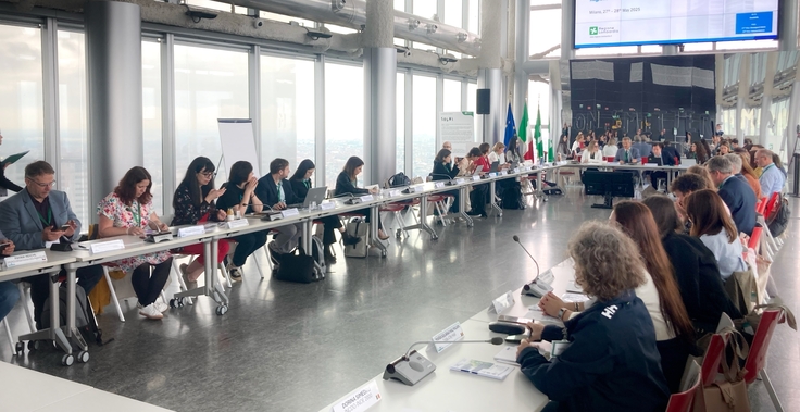 Menschen sitzen an als Rechteck angeordneten Tischen