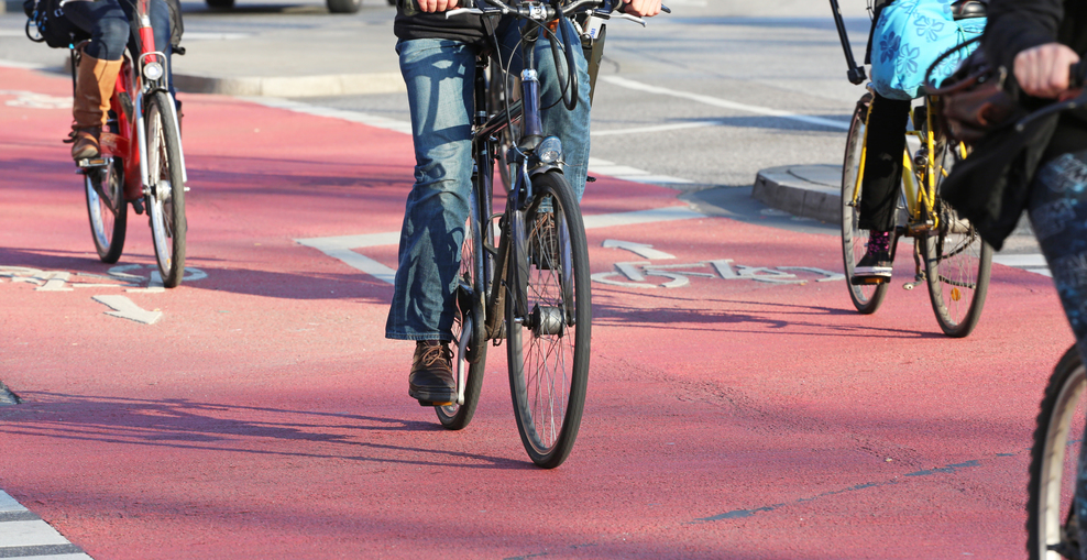 Mehrere Fahrradfahrer fahren auf einem rot gekennzeichneten Radweg.