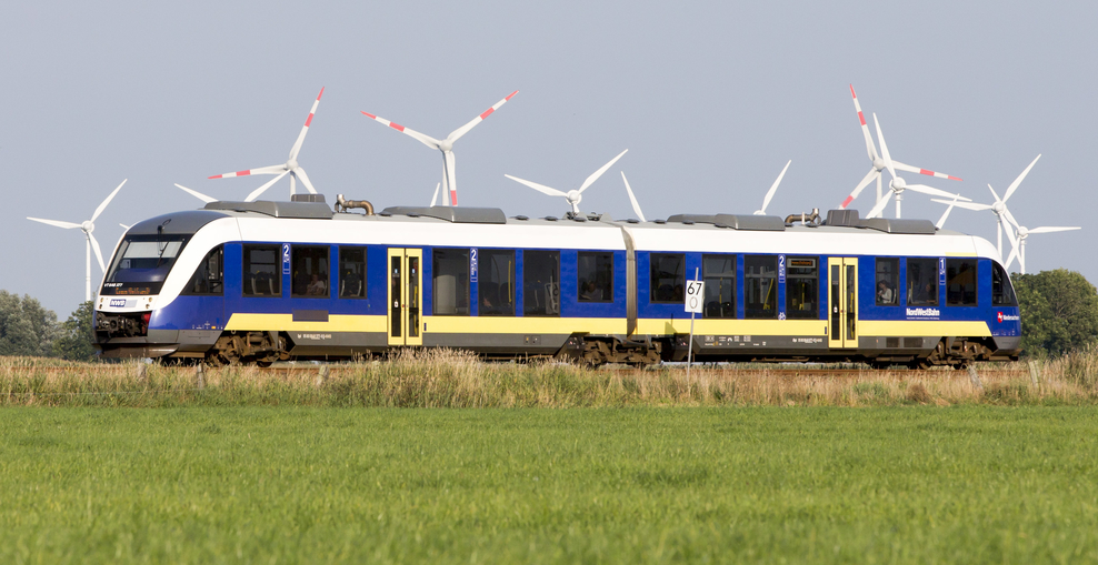 Blau-gelber Zug, im Hintergrund Windräder