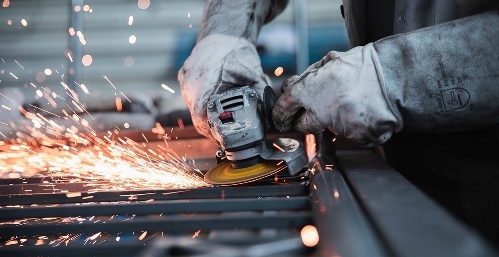 Arbeiter schleift mit Schleifmaschine Metallteil ab